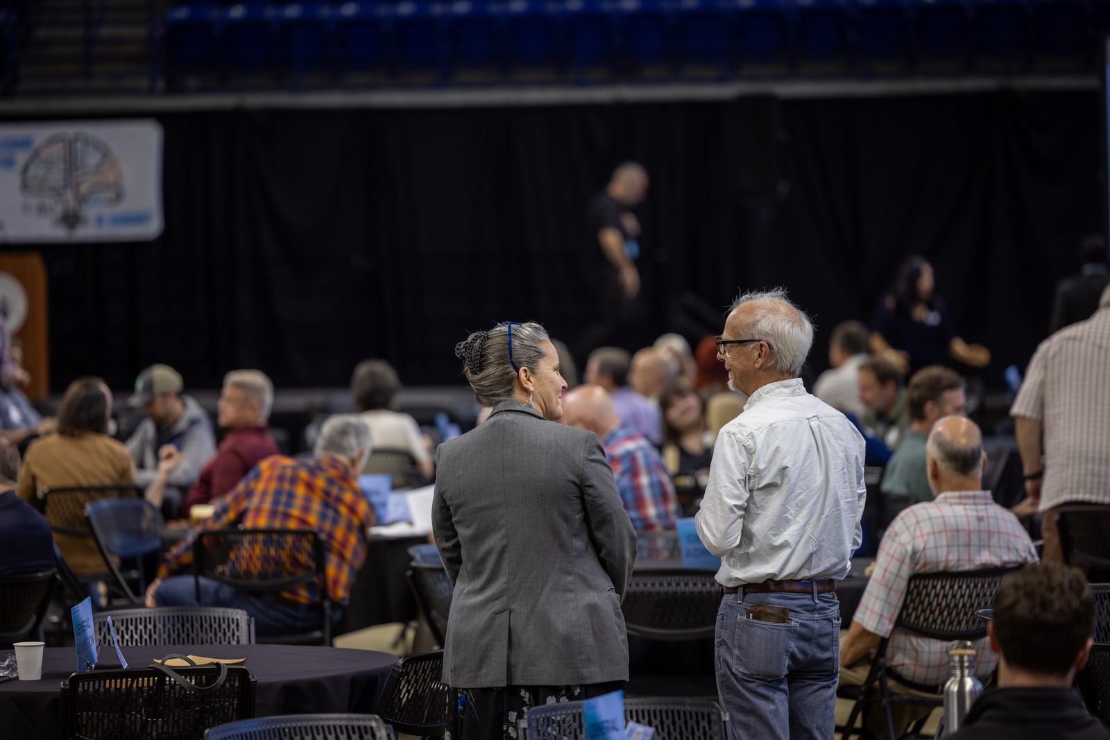 Two educators talking beside round tables at Brainhub